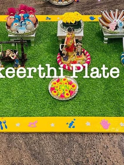 A closer look at a baby shower arrangement, featuring a miniature swing, cradle, and walker. These props add a playful and thematic touch to the seer varisai.