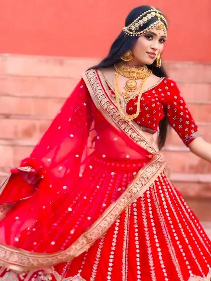 A vibrant red bridal lehenga with intricate silver and gold embroidery. The model's twirl showcases the beautiful flare of the skirt, making it a perfect choice for a bride who wants to feel like royalty.