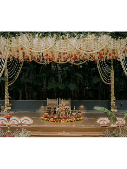 A straight-on shot of the mandap stage, highlighting the symmetrical floral arrangements and the traditional seating for the bride and groom.