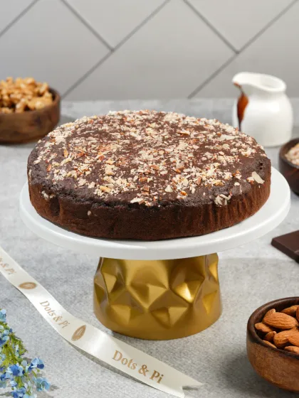 A full chocolate walnut cake presented on an elegant gold-accented stand. This type of hero shot is perfect for a bakery's homepage or promotional banner.