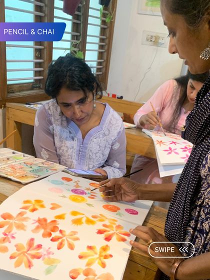 An instructor points out details on a student's floral watercolor painting. This kind of focused, individual feedback helps students refine their work and understand complex concepts.