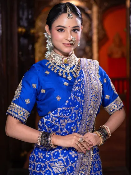 A portrait of poise and tradition. The soft lighting highlights the flawless skin work and the intricate details of her choker and nath.