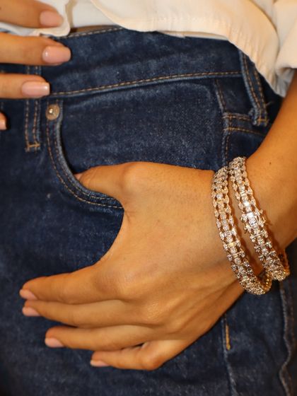 Your wrist deserves its own spotlight. A pair of our stunning diamond-studded gold bangles, shown here with a casual denim look to highlight their versatility.