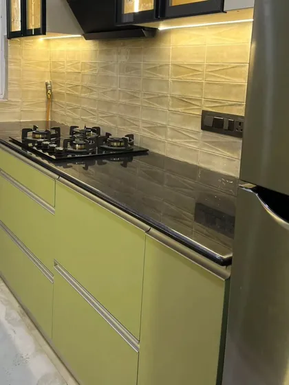 This handle-less design with G-profile channels gives the kitchen a clean, seamless look. The black granite countertop provides a durable and practical workspace.