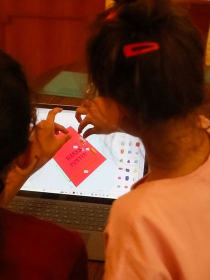 Two students collaborate on a 3D design, applying a digital sticker to their model. Teamwork makes the creative process even more fun.