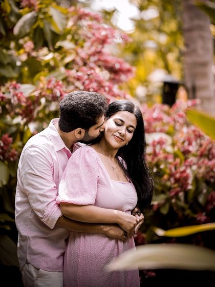 A tender kiss on the cheek, with the couple surrounded by a beautiful garden of pink flowers.