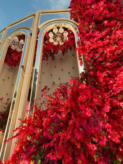 A low-angle shot of the mirrored arches, with a cascade of red flowers creating a stunning visual effect against the sky.