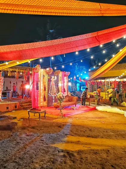 A wide view of an outdoor venue at night, showing the decorated stage and surrounding setup for a baby shower celebration.