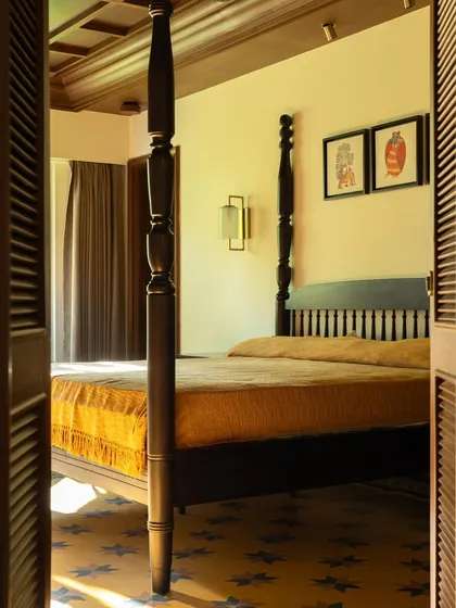 A glimpse into the bedroom through louvered wooden doors, a classic element of traditional Indian homes that allows for privacy and ventilation.