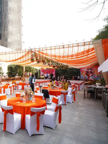 A wide shot of the dining area for the orange-themed corporate party. The bright orange linens and draped canopy created a cheerful and festive atmosphere for the team lunch.