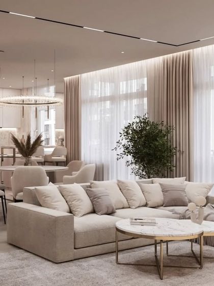 An open-concept living and dining space designed for a seamless flow. The neutral color palette, plush sectional sofa, and large windows create a bright, airy, and sophisticated home environment.