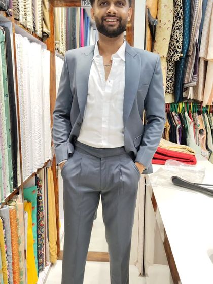 A full view of the client in his grey peak lapel suit, paired with an open-collar shirt for a sophisticated yet relaxed style.