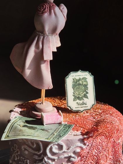 A close-up of the fashion designer cake, showing the intricate details on the edible mannequin and the personalized 'Nidhi' tag.