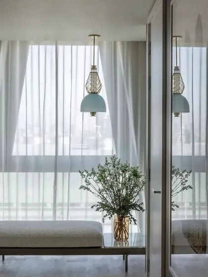 A single Luna Kaleido pendant adds a touch of artistry to a serene seating nook. The soft colors of the glass create a gentle focal point in the light-filled space.