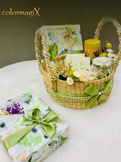 A charming Rakhi gift set featuring a woven basket with a green ribbon, accompanied by a beautifully wrapped gift box in a matching floral print. It's a complete and elegant solution.