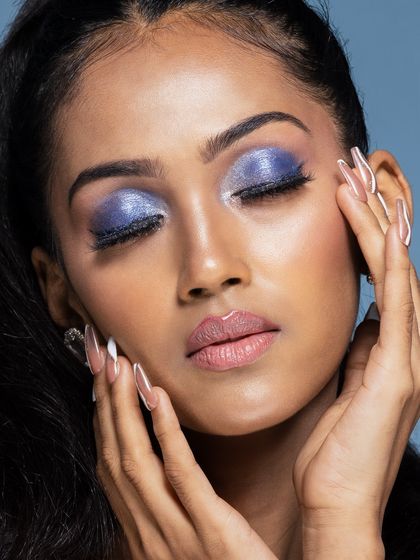 A serene beauty portrait with eyes closed, showcasing a beautiful shimmery purple eyeshadow look. The focus is on the artistry of the makeup.
