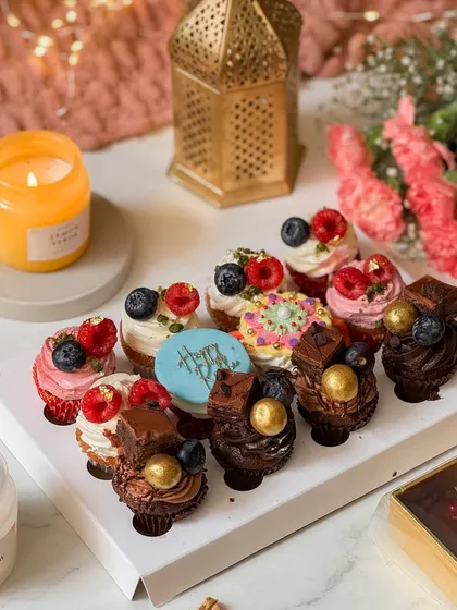 A box of twelve assorted mini cupcakes, beautifully decorated with fresh berries, chocolate, and a "Happy Rakhi" plaque. These bite-sized delights are perfect for sharing and celebrating together.