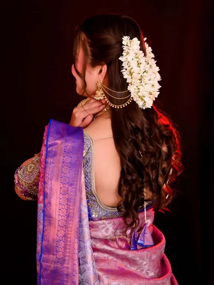 A back view of a South Indian bridal hairstyle, featuring beautiful curls and fresh flowers.