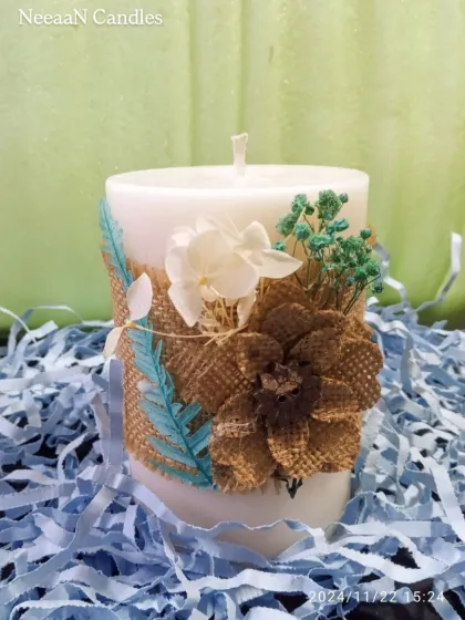 Handcrafted elegance in every detail. This rustic floral pillar candle is wrapped in burlap and decorated with dried flowers, bringing warmth, charm, and a touch of nature to your space.