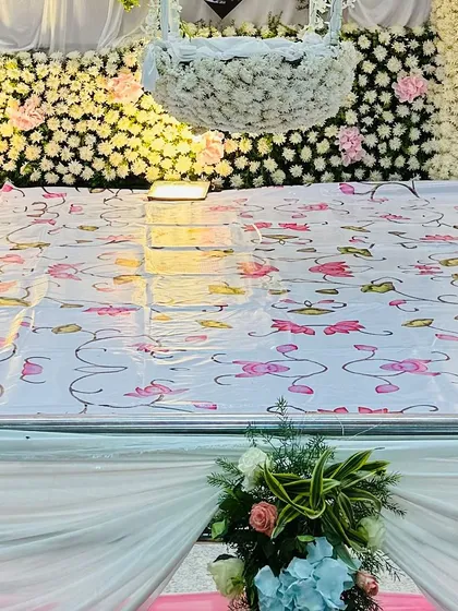 This image highlights a hanging cradle, or 'thottil', completely covered in white flowers. It is set against a dense flower wall, creating a dreamy and ethereal look for a naming ceremony.