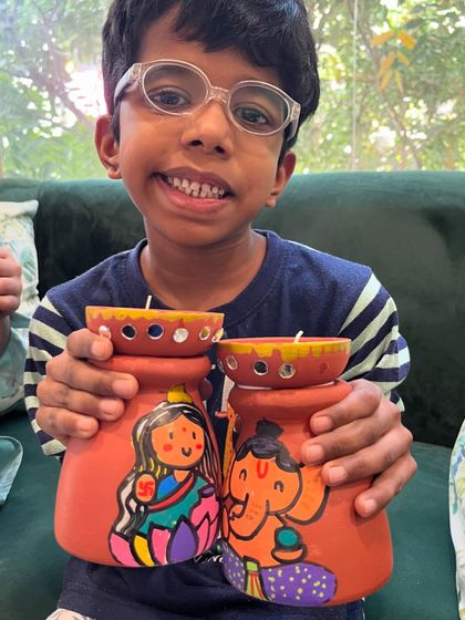 Look at the happy smile on this student's face as he shows the Lakshmi-Ganesha pots he painted.