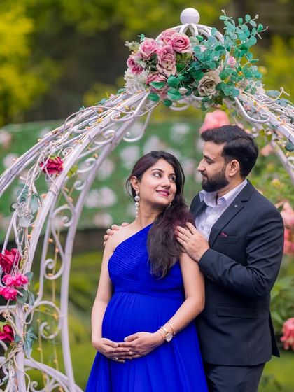 A sweet maternity moment by the white Cinderella carriage, with the surrounding flowers adding to the romantic, fairytale atmosphere.
