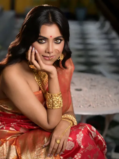 A seated portrait from the Sananda cover shoot, showcasing the full elegance of the traditional attire. The pose is graceful and contemplative, drawing attention to the handcrafted gold bangles and necklace.