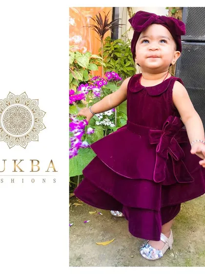 This little one is radiating pure joy in her custom-designed velvet party dress. I crafted this piece with a rich magenta velvet, featuring a playful tiered skirt, a classic Peter Pan collar, and a matching statement bow headband to create a look that's both whimsical and elegant for any celebration.