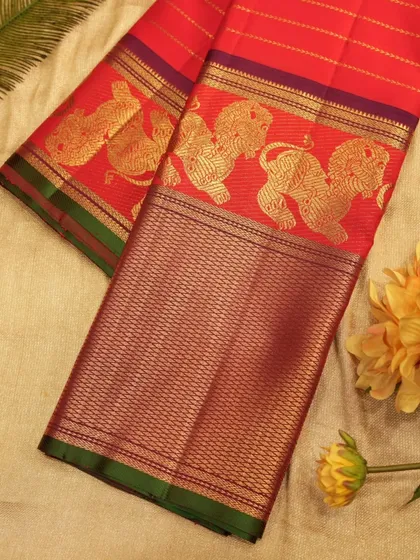 A bold and regal red Kanjivaram saree designed for a bride. This stunning piece features grand borders with mythical Yalli motifs woven in pure gold zari, symbolizing power and grace.