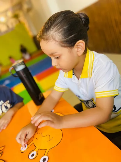 A close-up of a student's hands as he carefully works on his craft, showing the development of fine motor control.