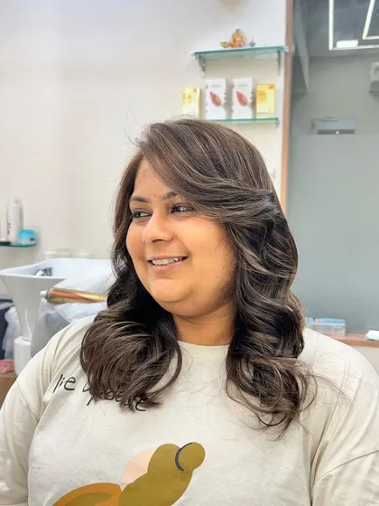 This client is all smiles with her new hair color. The soft waves and side-swept style perfectly showcase the blend of highlights and the overall healthy shine.