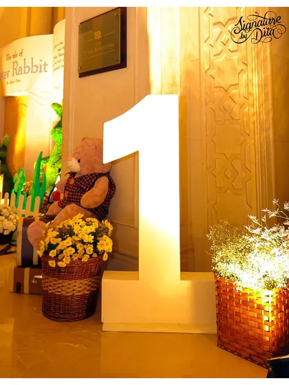 A large, illuminated number '1' next to a Peter Rabbit backdrop, marking the special milestone of the first birthday.