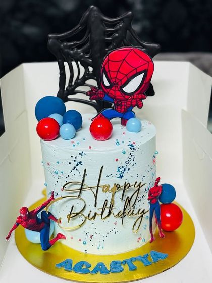 A detailed Spider-Man themed cake with a web background and city skyline accents.