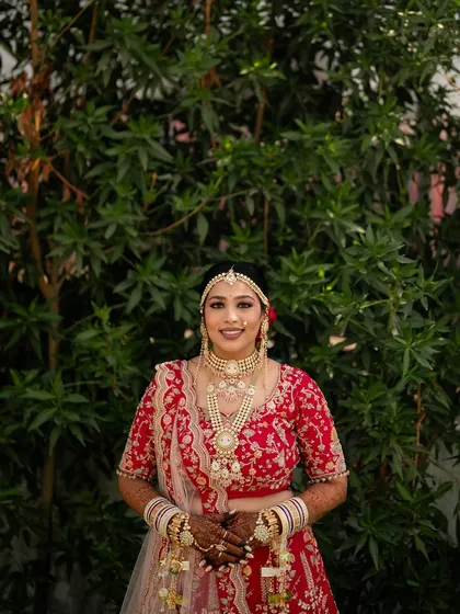 A beautiful portrait of the bride against a lush green background, her red outfit creating a striking contrast.