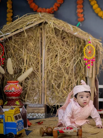 A curious baby exploring the Lohri setup, crawling towards a miniature truck. The details in the background bring the festive scene to life.