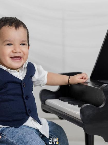 A sweet, smiling portrait of the baby at his piano.