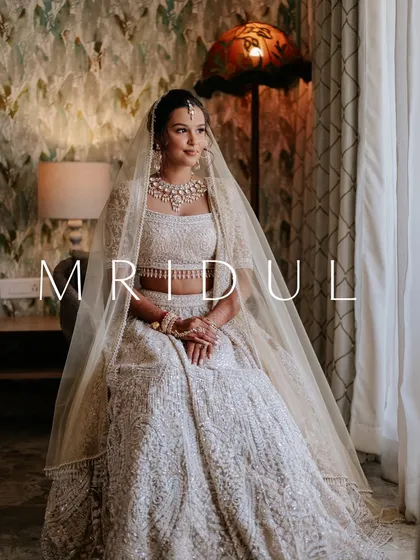 A full-length portrait of a bride in her stunning white lehenga. The soft natural light and her elegant pose create a picture of pure grace and beauty.