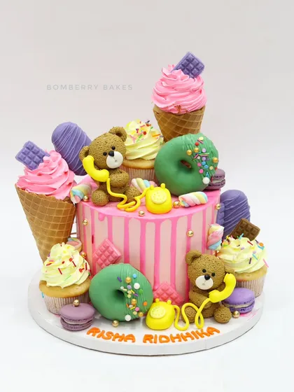A "candyland" cake for twins, overloaded with edible treats like ice cream cones, donuts, macarons, and teddy bear figurines.
