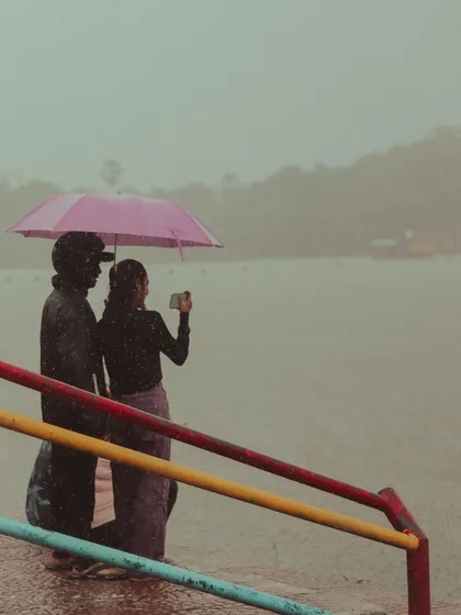 A couple takes a photo by the colorful railings of Powai lake, sharing a moment under a pink umbrella. The monsoon is full of these small, romantic scenes.