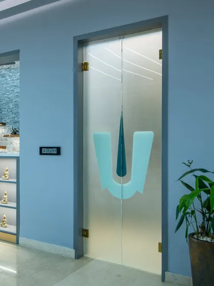 A custom frosted glass door with a 'Thirunamam' symbol, creating a respectful and beautiful separation for the pooja space.