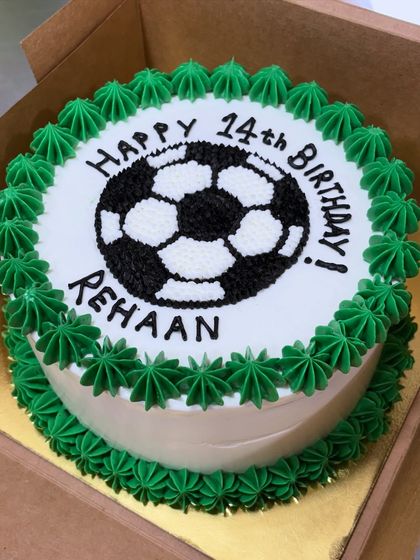 A classic soccer-themed birthday cake for Rehaan's 14th birthday. The design features a hand-piped soccer ball and a green star-piped border.