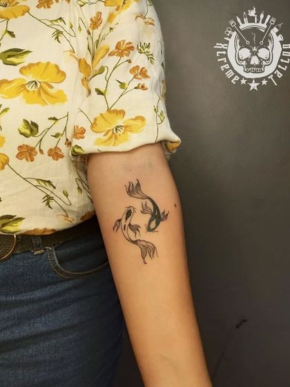 Two small koi fish swimming in a circle on the forearm. This is a minimalist take on a traditional symbol of balance, harmony, and good fortune.