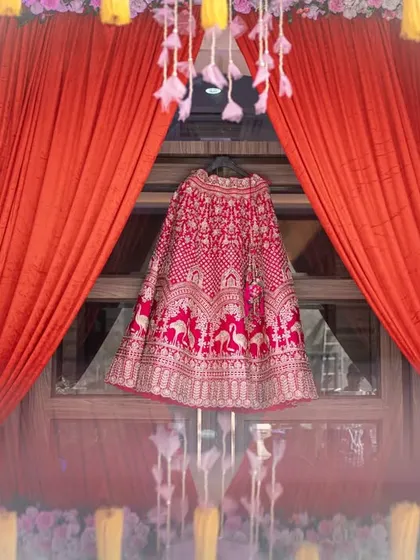 An artistic shot of the bridal lehenga, beautifully displayed against a window and framed by vibrant curtains. I see the dress not just as an outfit, but as a central character in the day's story.