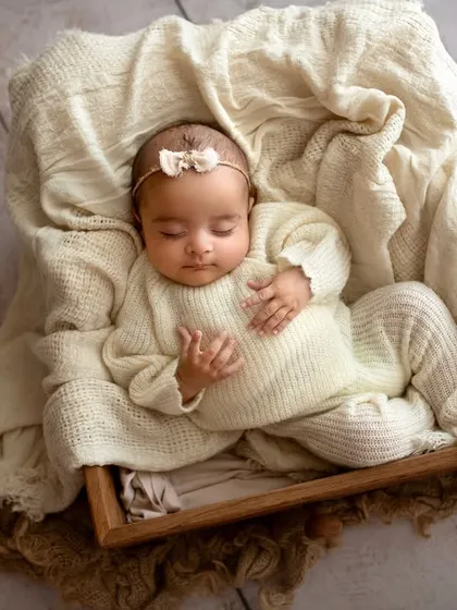 I believe in keeping things simple to let your baby's sweetness shine. This little one is sleeping peacefully in a cozy wooden box, nestled in soft, cream-colored knits, a perfect example of my safe and classic newborn photography style.