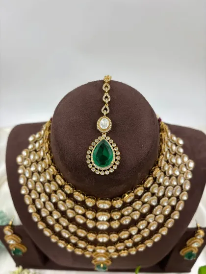 Our multi-layered Rani Haar sets are a bestseller. This piece showcases six layers of uncut Polki-style stones with a stunning emerald green pendant and matching earrings, offering a truly royal look for weddings and grand occasions.