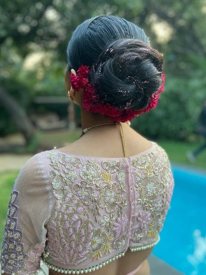 A full view of the high bun with red coxcomb flowers, a perfect hairstyle for a bride who wants a touch of drama and tradition.