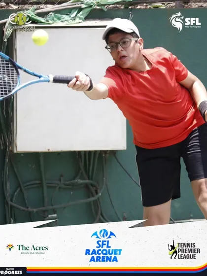 A player in a red shirt focuses intently as he makes contact with the ball on a forehand shot, demonstrating precision under pressure.