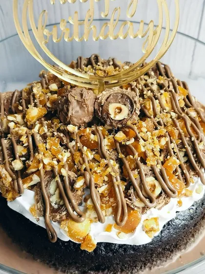 A close-up of the Choco Rocher Tres Leches, highlighting the irresistible textures of crunchy hazelnut praline, creamy frosting, and a whole Ferrero Rocher.