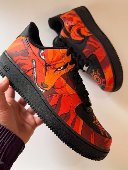 A view of the outer side of the Kurama AF1, showing the piercing red eyes and fierce expression of the Nine-Tails beast. The artwork is designed to flow across the panels of the shoe.