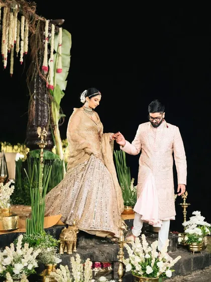 The couple's first steps as husband and wife, descending from the beautifully detailed South Indian mandap. The design incorporates natural stone steps, brass lamps, and lush florals.